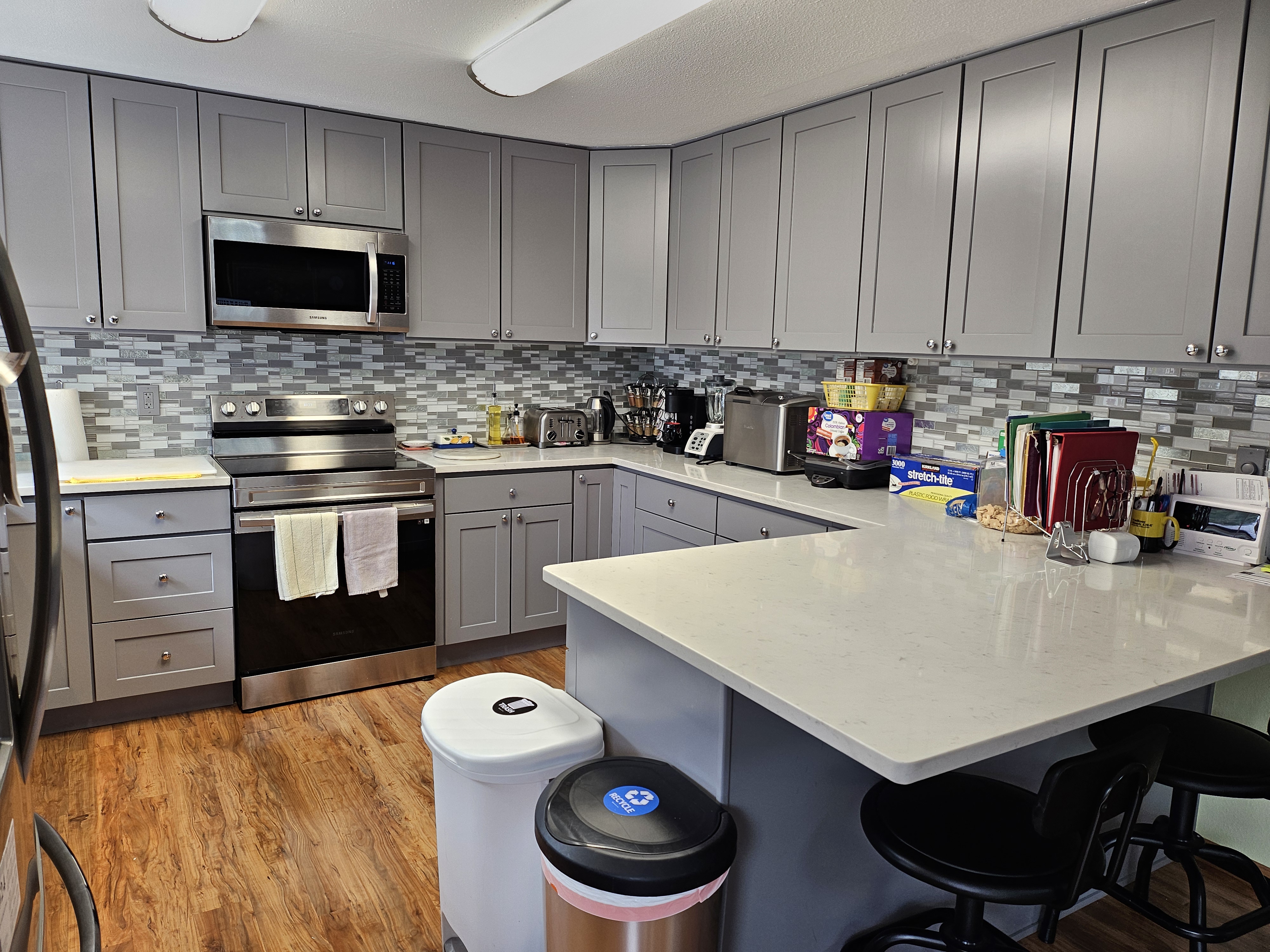 A nurse sits on a bed holding hands with an elderly woman, both smiling and engaged in conversation in a well-lit room at one of the welcoming Snohomish County adult family homes.